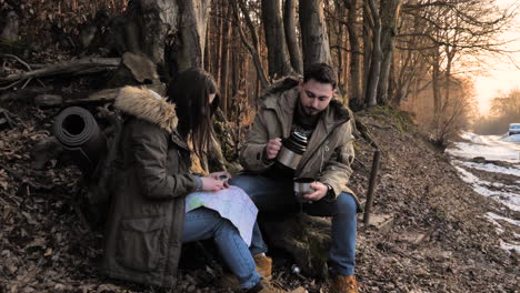 una pareja caucásica revisando el mapa en un bosque.