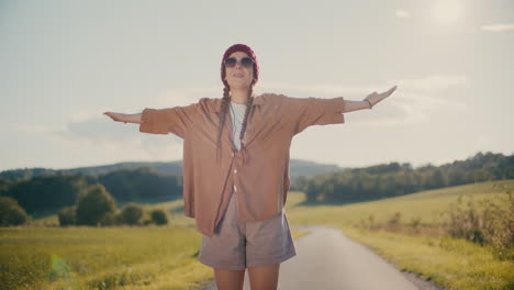 carefree woman with arms outstretched standing on footpath