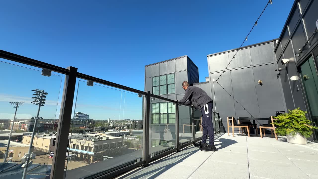Caucasian man with sunglasses standing alone on rooftop building enjoying view of city on sunny day