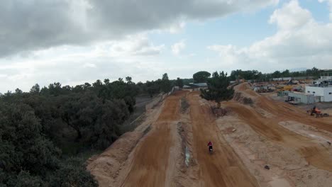 Rückansicht-Des-Motocross-Fahrers-Direkt-Auf-Der-Unbefestigten-Strecke-Mit-Bewölktem-Himmel