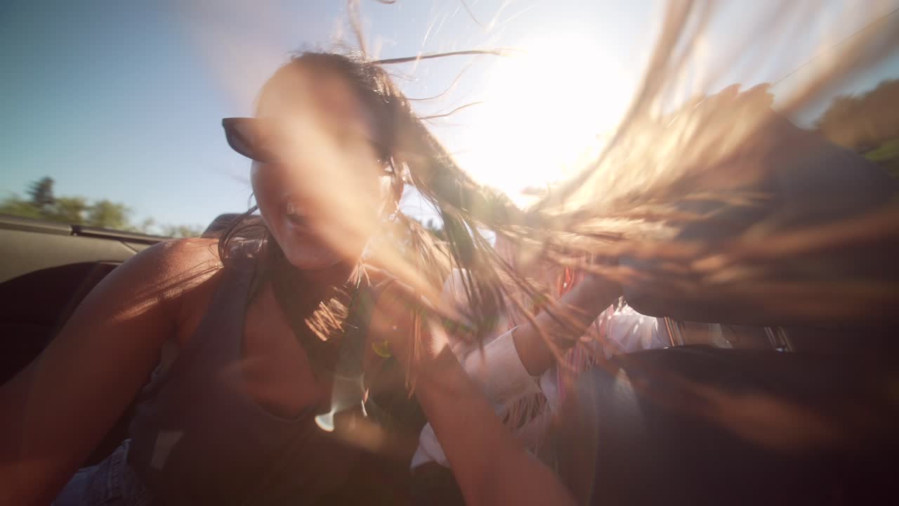 Two happy women enjoying a convertible car ride on a sunny day