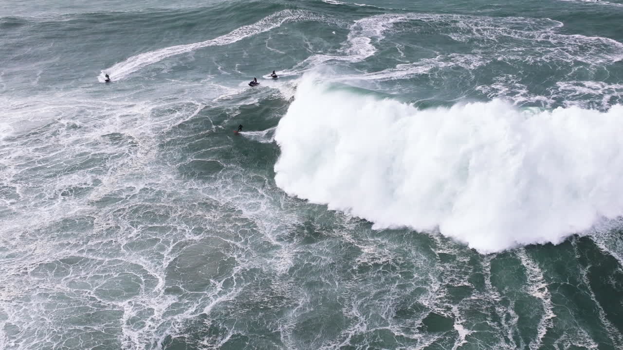 Aerial drone shot of big wave surfer surfing a giant wave and celebrating in Nazare, Portugal, Europe. Nazaré, big wave surfing town with biggest waves in the world. Shot in ProRes 422 HQ