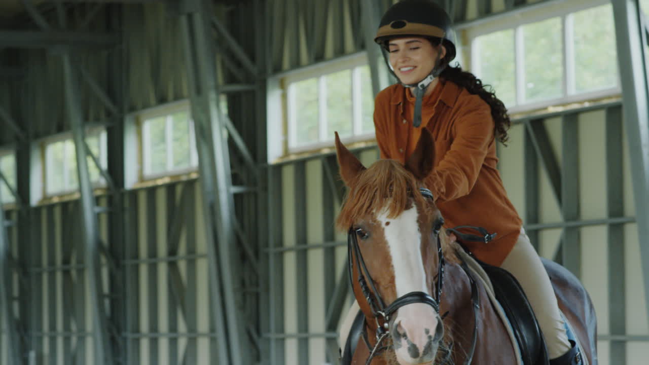 Young woman horseback riding in an indoor arena