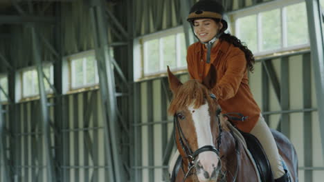 young woman horseback riding in an indoor arena