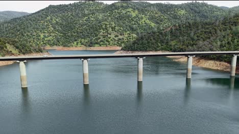 an aerial view of a vehicle making its way over the don pedro reservoir bridge, with the lake stretching into the distance.