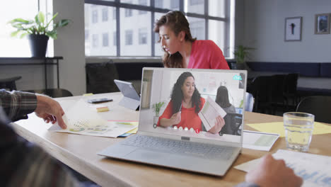 Caucasian-businessman-on-laptop-video-call-with-biracial-female-colleague-on-screen