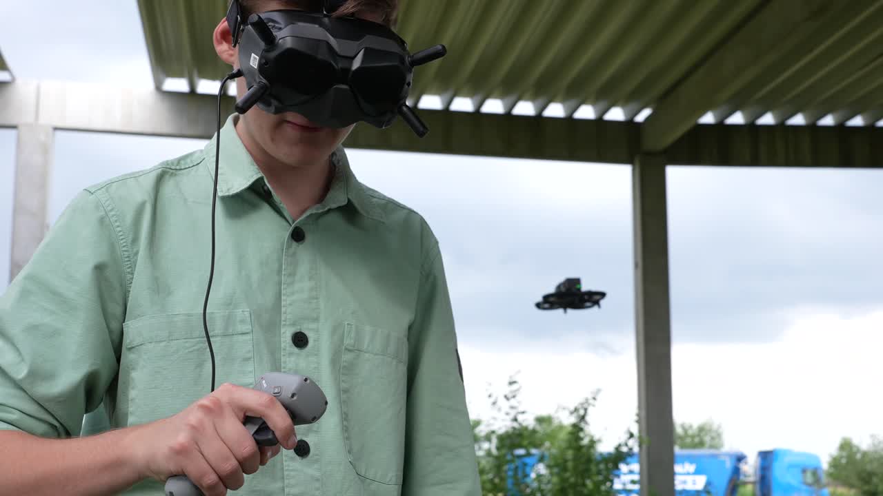 primer plano de un joven que controla un dron fpv con gafas, auriculares y controlador de movimiento remoto