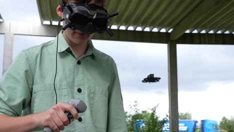 close up of young man controlling fpv drone with goggles headset and remote motion controller