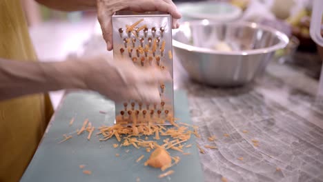 crop woman grating fresh carrot in kitchen