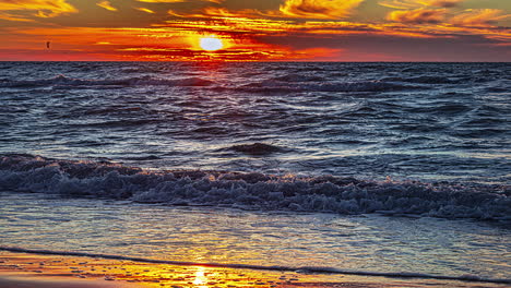 Tiro-De-Lapso-De-Tiempo-De-Las-Olas-En-El-Mar-Báltico-Con-Mucha-Gente-Caminando-En-La-Orilla-Durante-La-Puesta-De-Sol-Dorada