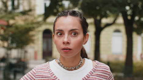 amazed woman open mouth looking surprised through street with big open eyes shocked by something