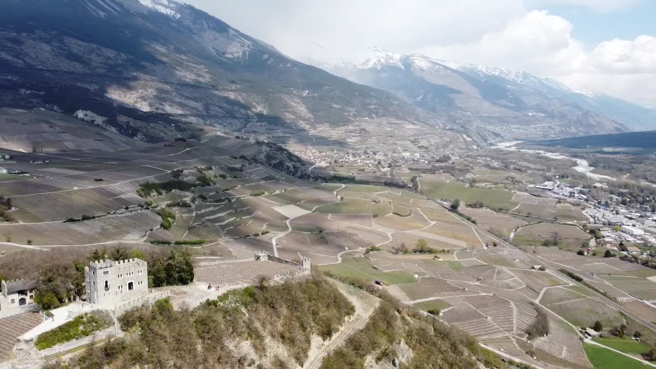 pequeño castillo en medio de un valle verde en suiza, con sombras de las nubes