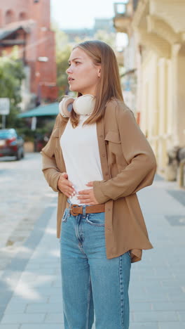 young woman experiencing stomach pain on city street