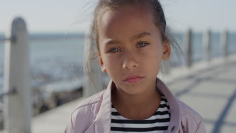 portrait young little mixed race girl looking serious contemplative kid on sunny seaside beach real people series