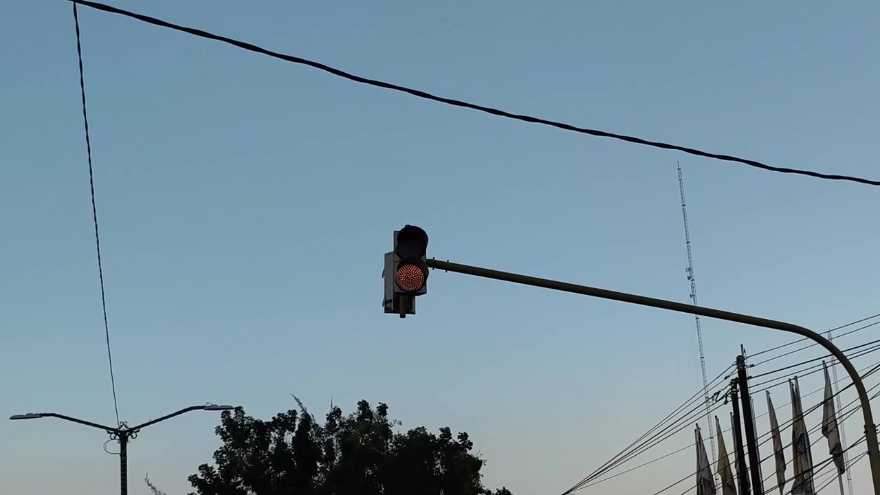 Lampu Lalu Lintas Berkedip Merah dengan Latar Langit Biru Cerah