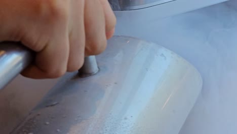 person pouring liquid nitrogen on ice cream maker machine mixer