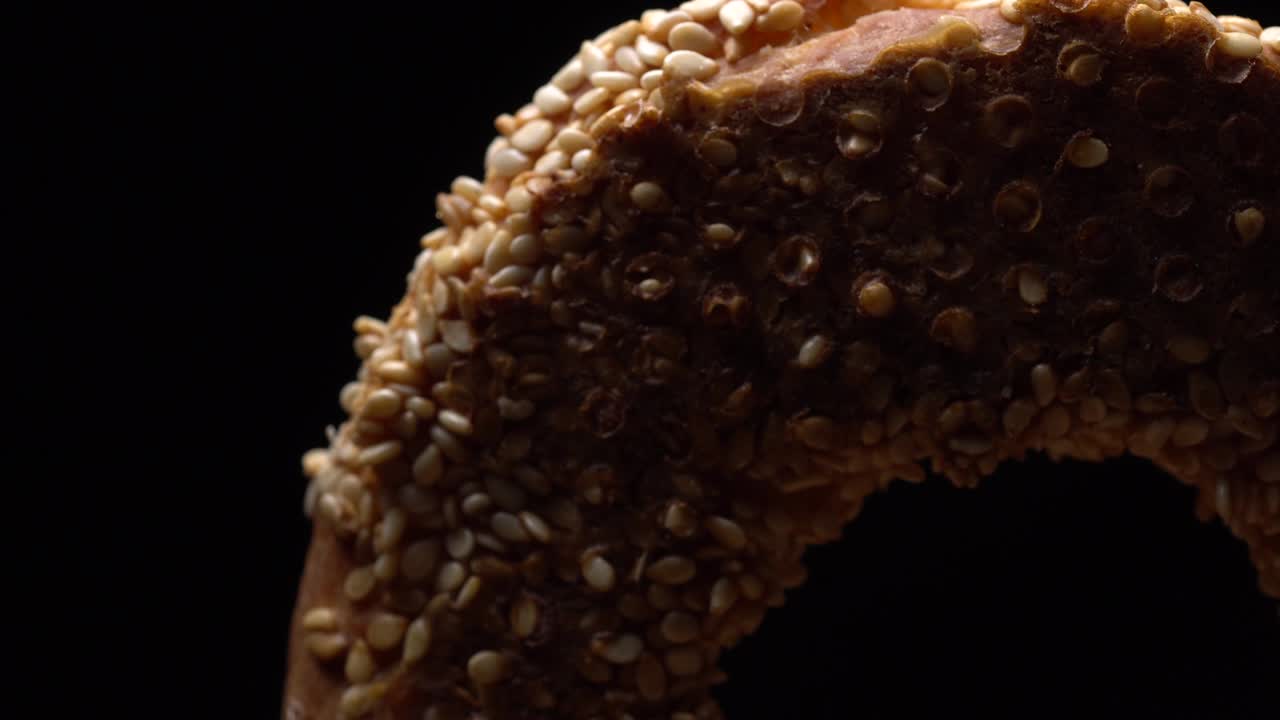 bagels frescos con semillas de sésamo en rotación. fondo negro. primer plano extremo.