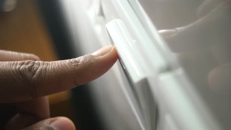 Finger Pressing a Button on a White Appliance