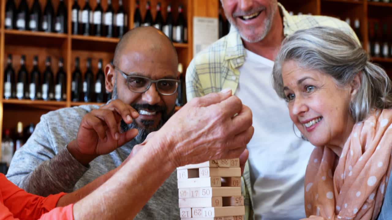 Amici felici che giocano a Jenga mentre bevono caffè 4k