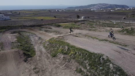 drone shot of two motocross riders on as they hit a jump on dirt track