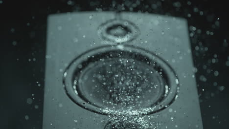 a thumping speaker blows out a pile of silver glitter