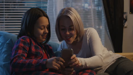 mother and daughter using a smartphone at night