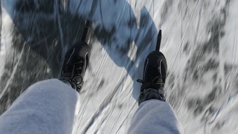 top view of man legs are skating on thick ice on river in winter. male in black skates is skating on frozen lake. winter sport activities