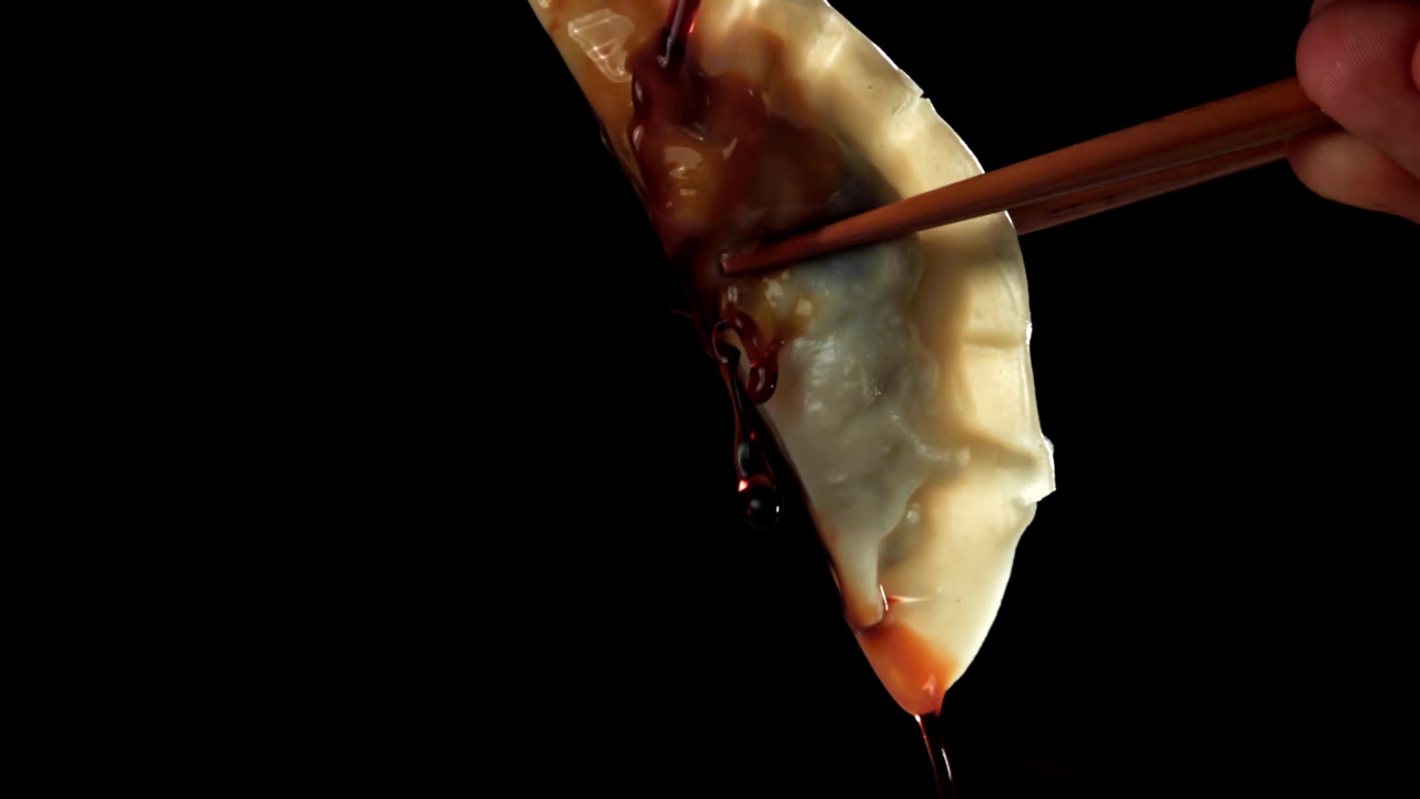 Slow Motion of Soy Sauce Being Poured on a Dumpling Held by Chopsticks