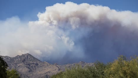 timelapse of dense smoke above mountain peaks going into atmosphere on sunny day