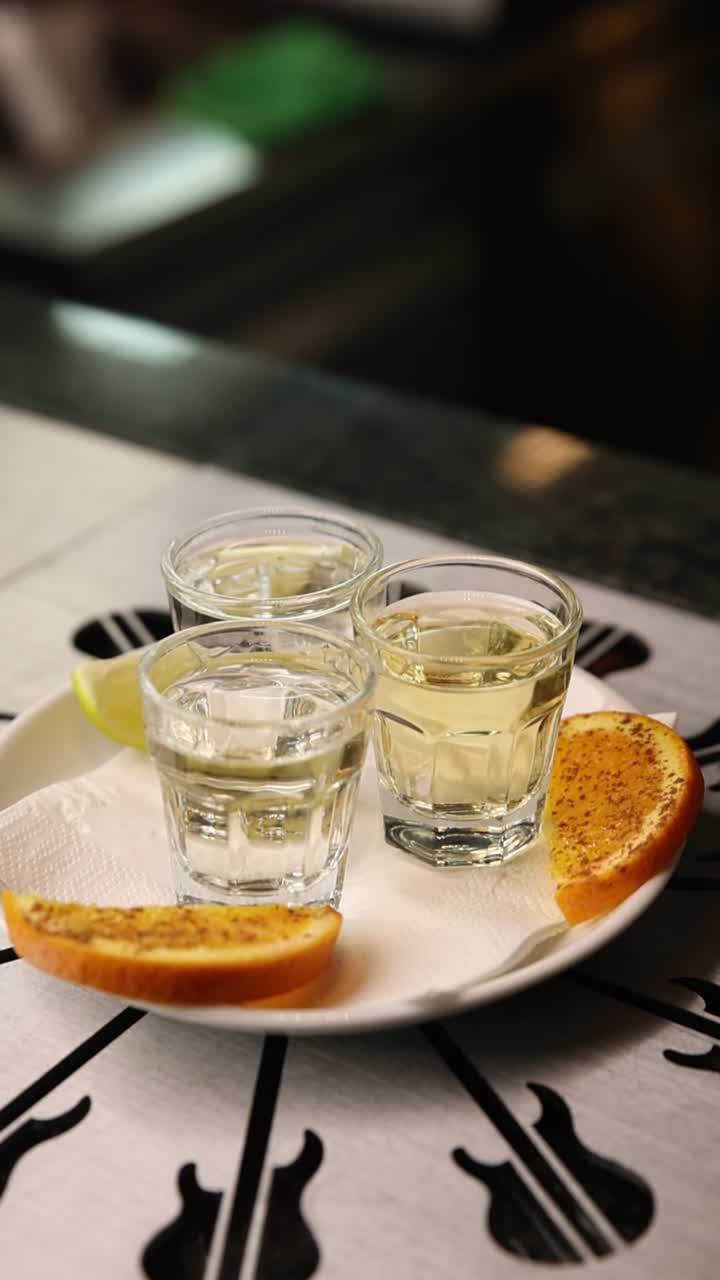 Primo piano di cicchetti di tequila serviti con lime e arancia speziata
