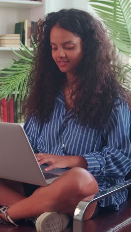 young happy casual indian woman freelancer performs remote work via laptop