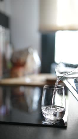 pouring water into a glass in a kitchen