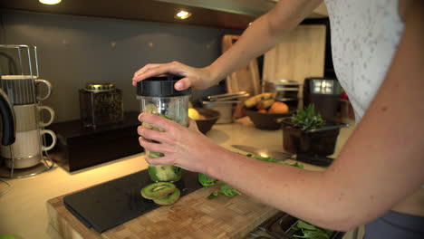 mujer joven colocando la tapa en la taza de la licuadora