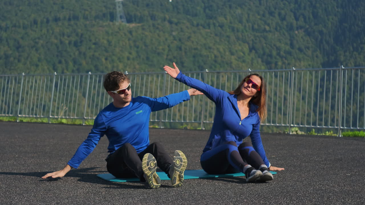 pareja estirándose al aire libre en una vista de montaña