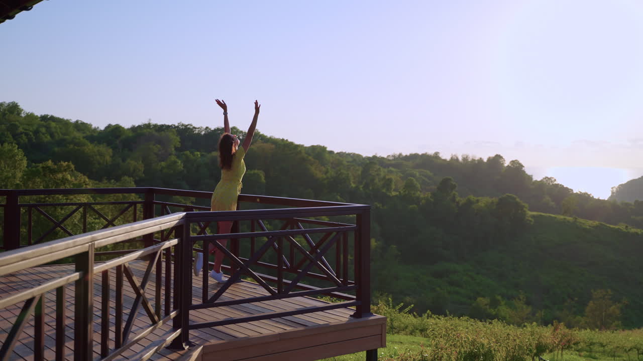 mujer disfrutando de una vista desde un balcón de montaña al amanecer o al atardecer