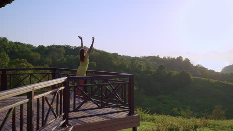 woman enjoying a view from a mountain balcony at sunrise/sunset