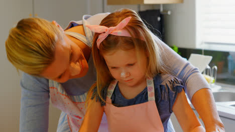 front view of young caucasian mother and daughter rolling dough in kitchen of comfortable home 4k