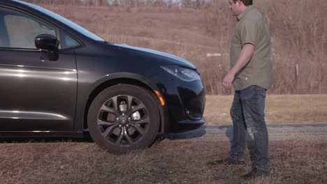 Man-upset-about-a-flat-tire-on-side-of-the-interstate