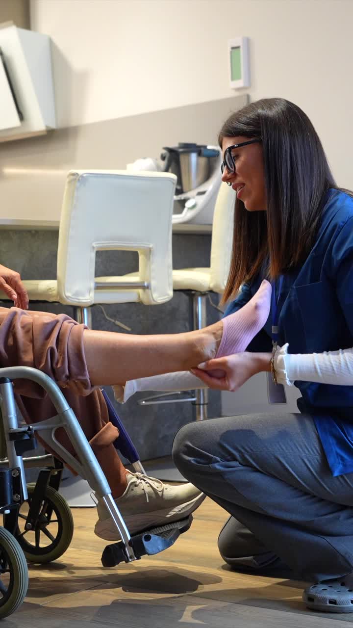 Enfermera atendiendo las piernas de un paciente en silla de ruedas