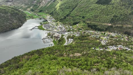 aerial approaching hellesylt village close to geiranger fjord in western norway - local town with cruise and ferry quays seen during springtime