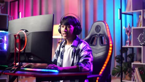 un adolescente asiático emocionado jugando a videojuegos en la computadora