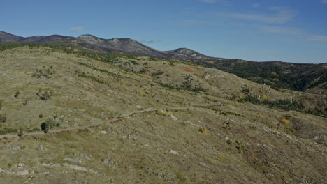 Antena-En-órbita-Mientras-Un-Coche-Pequeño-Viaja-Por-Una-Carretera-Remota-En-La-Ladera-De-Una-Montaña,-4k