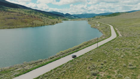 suv truck drives along country road by a small lake