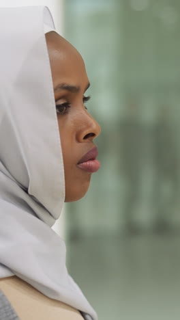 thoughtful black woman with hijab on head looks around in shopping center slow motion. muslim lady visits trade mall unaccompanied closeup. arabic old traditions