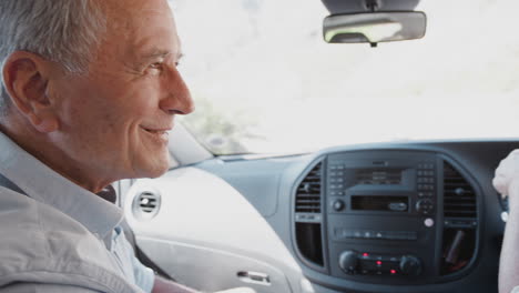 Interior-View-Of-Senior-Couple-On-Vacation-Driving-Hire-Car-Along-Country-Road