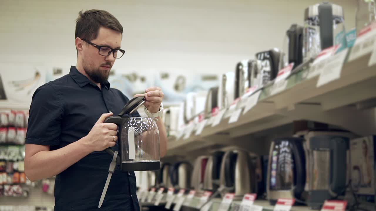hombre mirando una tetera en una tienda de electrodomésticos