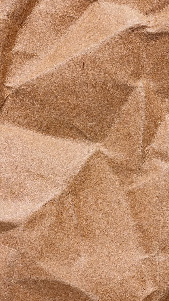 Portrait stop motion loop of crumpled brown kraft wrap with soft shadows