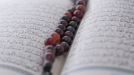 holy book quran and prayer beads on table, close up.