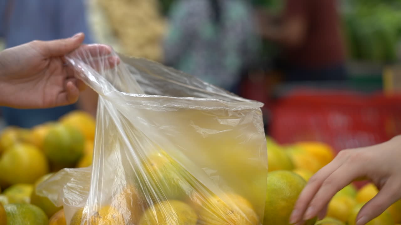농산물 가게나 슈퍼마켓에서 오렌지를 고르는 여성의 손 - 고립