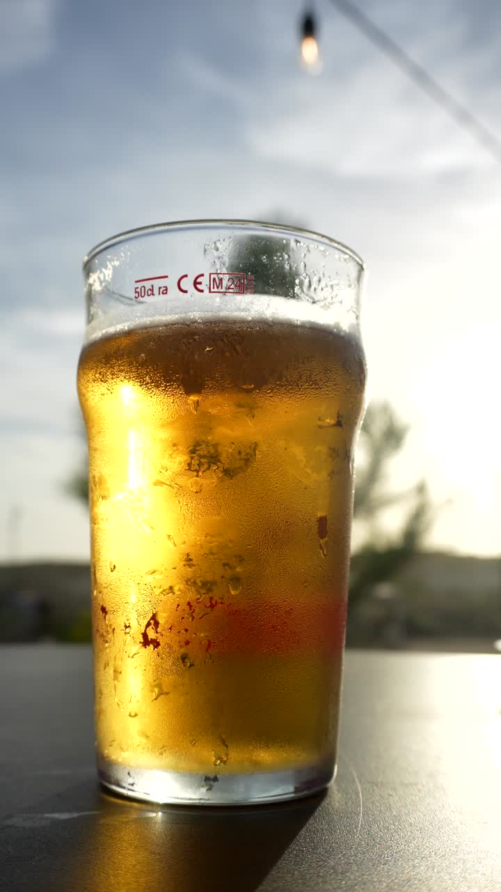 Mano che prende un bicchiere di birra fredda in una giornata di sole